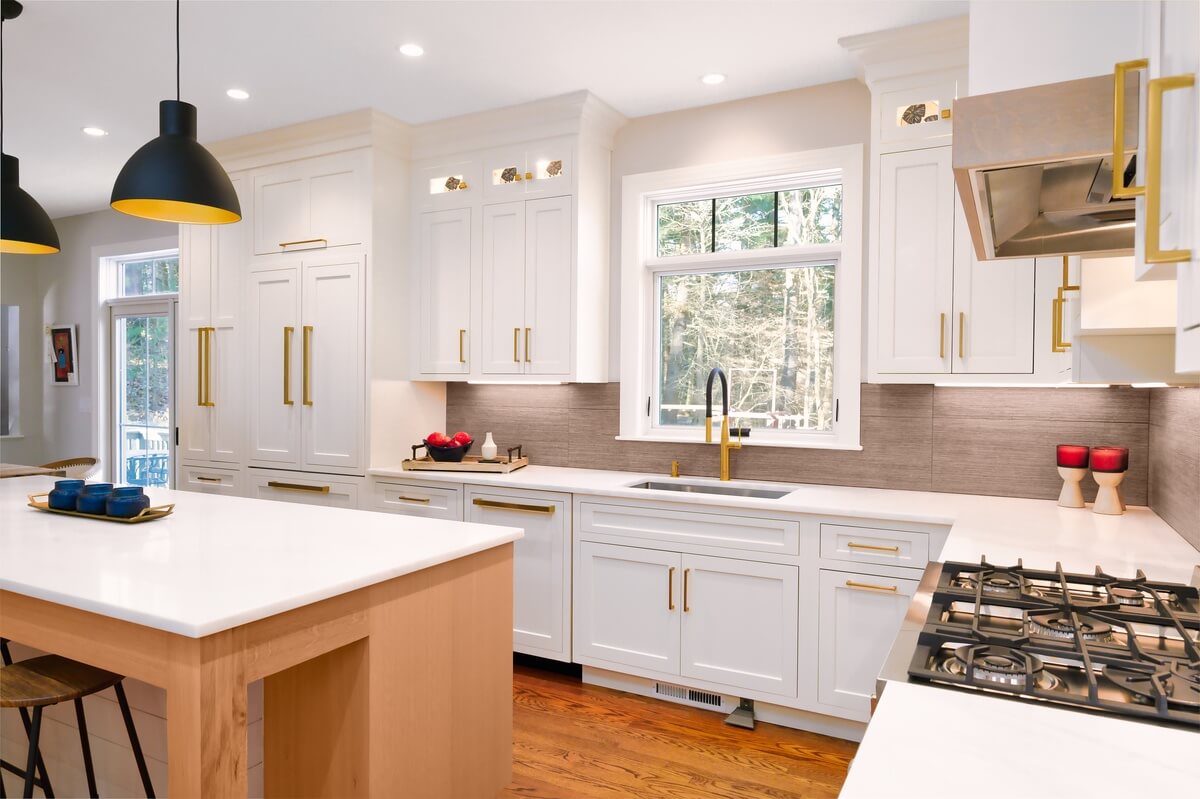 Modern white kitchen interior with island, built-in appliances, and gold accents