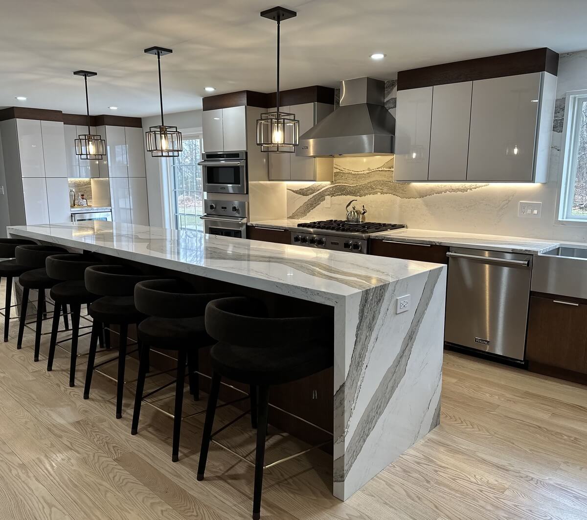 Modern kitchen with marble waterfall island, custom cabinetry, and stone tile backsplash